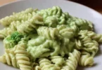 Creamy avocado broccoli pasta served in a bowl with fresh herbs on top