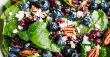 Blueberry spinach salad topped with honey balsamic dressing and fresh ingredients.