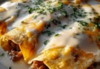 Delicious breakfast enchiladas topped with creamy sausage gravy ready to serve.