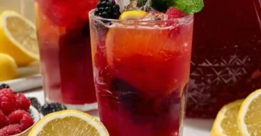 A refreshing glass of easy homemade triple berry lemonade with vibrant berries and lemon slices.