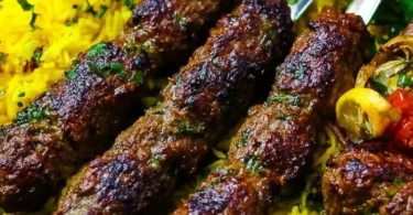 Plate of juicy Middle Eastern kebabs served with fresh vegetables and sauces.