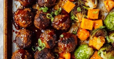 Juicy Korean BBQ meatballs on a plate garnished with sesame seeds and herbs.