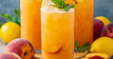 Refreshing glass of peach lemonade with fresh peaches and lemon slices