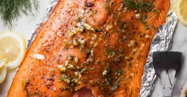 Homemade smoked salmon on a wooden board with herbs and lemon slices